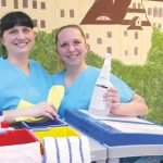zwei Mitarbeiterinnen der Unterhaltsreinigung stehen am Putzwagen